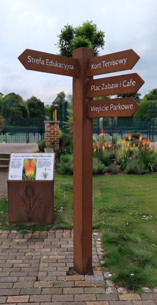 Wolnostojący parkowy drogowskaz pieszy ze stali corten z czytelnymi polskimi napisami na strzałkach kierunkowych